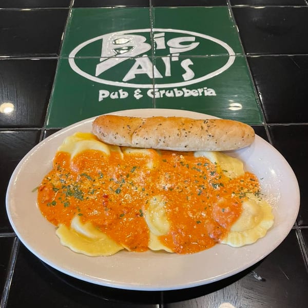Ravioli with red sauce and a breadstick on a plate, with the Big Al's Pub & Grubberia logo.